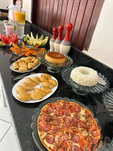 een tafel met borden eten en een pizza bij Pousada Flor de Ipê - Arraial d'Ajuda - a 100m da Rua do Mucugê - principal Rua da cidade in Arraial d'Ajuda