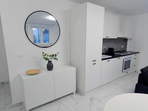 a white kitchen with a mirror on the wall at Casa Rossini - Moderno appartamento a due passi dal mare in Pescara