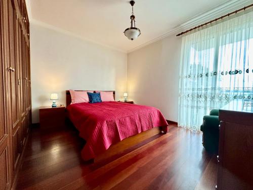 een slaapkamer met een bed met een rode deken en een raam bij Lido Funchal in Funchal