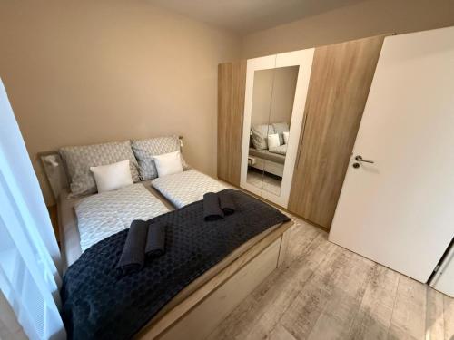 a small bedroom with a bed and a mirror at HIGHWAY Apartman in Győr