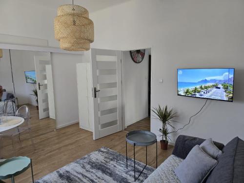 een woonkamer met een bank en een tv aan de muur bij Apartamenty CAPPUCCINO in Przemyśl