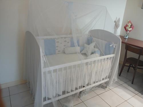 um berço branco com um dossel branco em um quarto em Lalas ASA em Praia