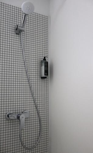a shower with a shower head on a tiled wall at ibis budget Lorient Hennebont in Hennebont