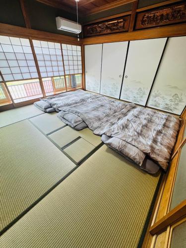 a large bed in a room with windows at ゲストハウス輪 高野山麓 in Hashimoto