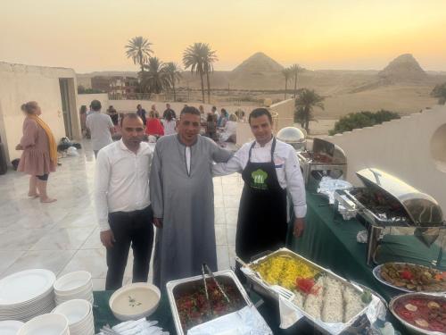 three men standing in front of a buffet of food at Sun Temple Palace in Cairo