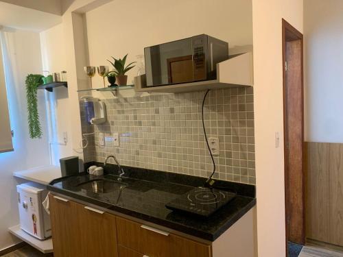 a kitchen with a sink and a microwave on the wall at Apê 301 a 2,8 km da UFV in Viçosa