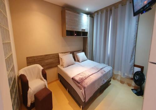 a small bedroom with a bed and a chair at Apartamento Estúdio 306 na ZN in Porto Alegre
