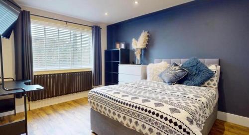 Un dormitorio con una cama y una pared azul. en The Bungalow by The Garden Spa Stays, 4 bed, Sauna - Hot Tub - Ice Bath, en Radstock