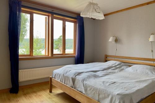 Un dormitorio con una cama y dos ventanas en Idyllic Lake House in Sweden, en Klässbol
