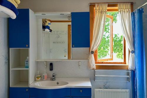 baño con armarios azules, lavabo y ventana en Idyllic Lake House in Sweden, en Klässbol