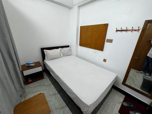 Un pequeño dormitorio con una cama blanca en una habitación en Hotel Tayef Dhanmondi, en Dhaka