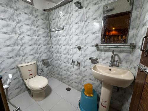 Un baño blanco con inodoro y lavabo. en Hotel Tayef Dhanmondi, en Dhaka