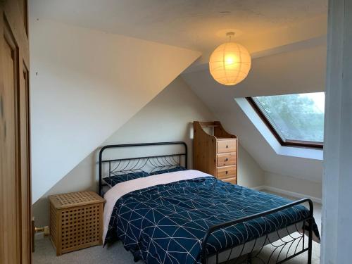 a bedroom with a bed with a blue comforter and a window at Grace Cottage-a 4 bedroom period cottage in Teignmouth