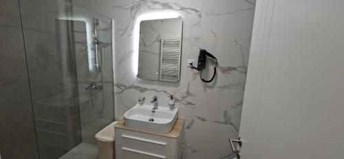 a white bathroom with a sink and a shower at Extra Apartman Palata in Banja Luka