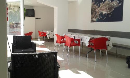 a room with red chairs and a table with a laptop at Albergue @ Muxia in Muxia