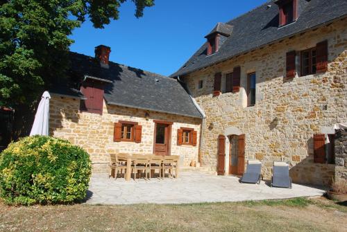 - un bâtiment en pierre avec une table et des chaises devant dans l'établissement Les Charmes de Grèzes- location de samedi à samedi, à Grèzes