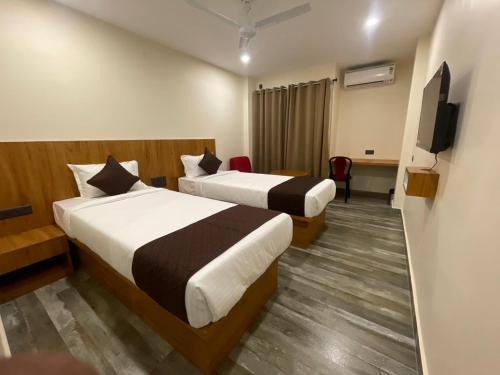 a hotel room with two beds and a flat screen tv at The Imperia in Guwahati
