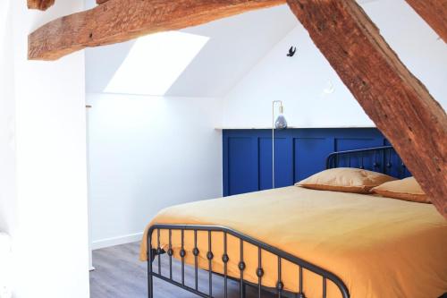 un dormitorio con una cama con cabecero azul en L'atypique des choux, en Les Choux