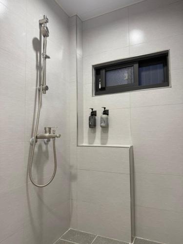 a white bathroom with a shower with a window at Jian Guo Hotel in Pingtung City