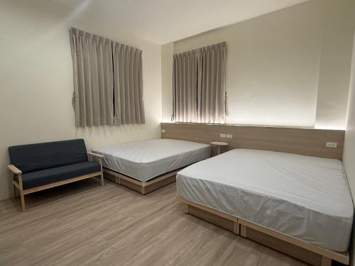 a room with two beds and a chair in it at Jian Guo Hotel in Pingtung City