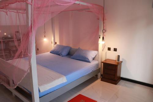 a bedroom with a white bed with a pink canopy at Pabalu House in Ahangama