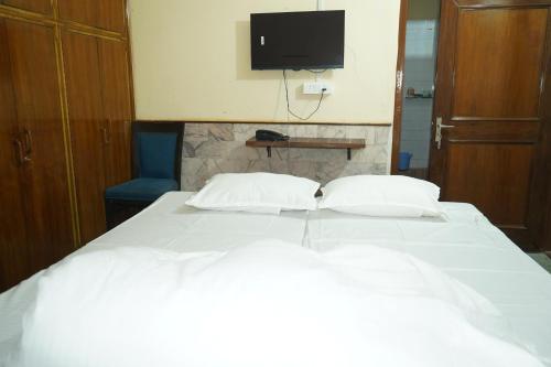 a bedroom with a white bed with a tv on the wall at Hotel BLUE DIAMOND in Begusarai