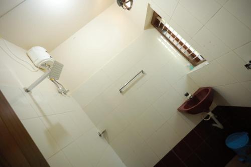 a white bathroom with a toilet and a sink at Smiley Homestay in Varkala