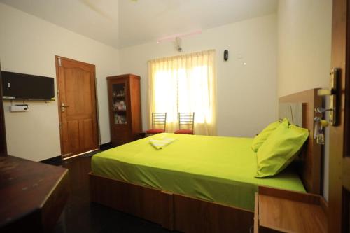 a bedroom with a green bed and a window at Smiley Homestay in Varkala