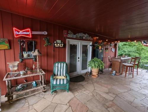 une terrasse couverte d'une maison avec une chaise verte dans l'établissement Romantic Suite Rental with Terrace and Chimenea near Gatlinburg, Tennessee, à Rivertrace