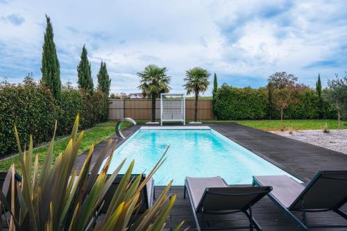 a swimming pool in a yard with chairs and trees at La Villa Marais in Déols