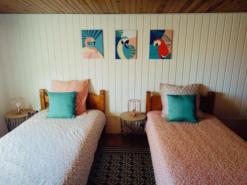 two beds in a room with pictures on the wall at La case d'Isabelle in Saint-Denis