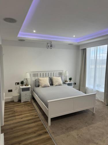 a bedroom with a white bed and a purple ceiling at Cinema room apartment 1 in Basildon