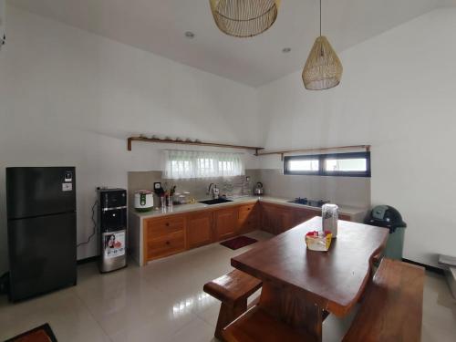 a kitchen with a wooden table and a black refrigerator at savilla1 4 kamar dobel bed kolam renang dan biliard in Tlekung