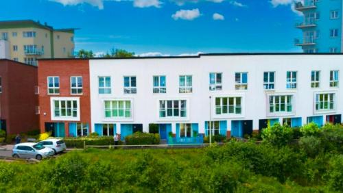 a large white building with cars parked in a parking lot at 4 bed Townhouse with spectacular views 4 miles from Cardiff 10min drive or train journey to city centre in Cardiff