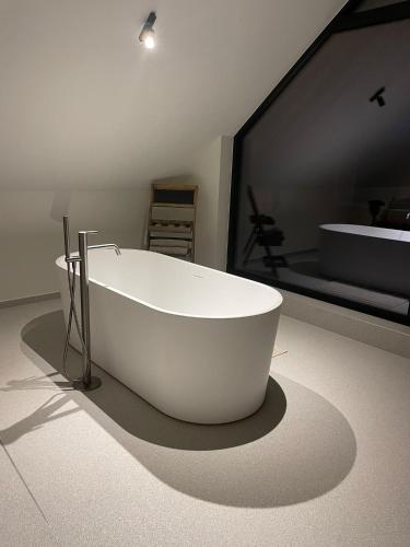 a white bath tub sitting on a floor in a bathroom at De Kempische Hoef in Westerlo