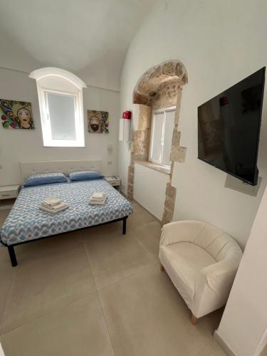 a bedroom with a bed and a tv and a chair at Kalsa’s House Noto in Noto
