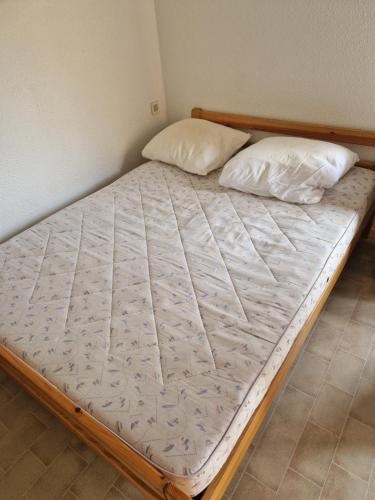 a bed in a room with two pillows on it at T2 familial climatisé mer à pied parking privé in Saint Cyprien Plage