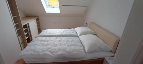 Una cama con sábanas blancas y almohadas en una habitación. en Apartmán Jana, en Vysoké Mýto