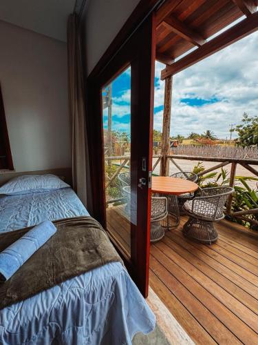 Un dormitorio con una cama y una mesa en una terraza. en Morros da Barra chalé 05, en Barra Grande