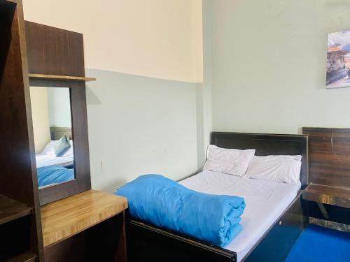 a bedroom with a bed with a blue blanket on it at Hotel MAQ Lumbini in Lumbini