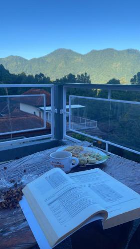 een tafel met een boek en een bord eten op een balkon bij As Family Villa in Singaraja