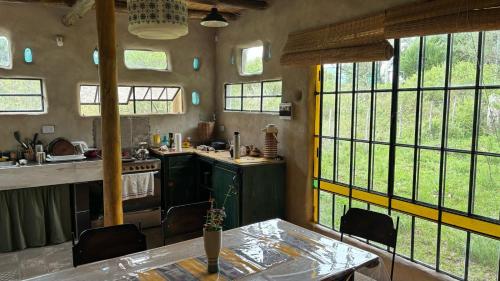 une cuisine avec une table et quelques fenêtres dans l'établissement Tierra de Arroyo, Mallin-Tanti, à Tanti