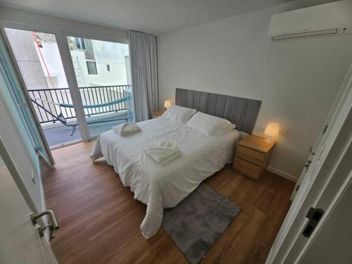 a bedroom with a bed with white sheets and a window at Apartamento Sonho Jardim in Ponta Delgada