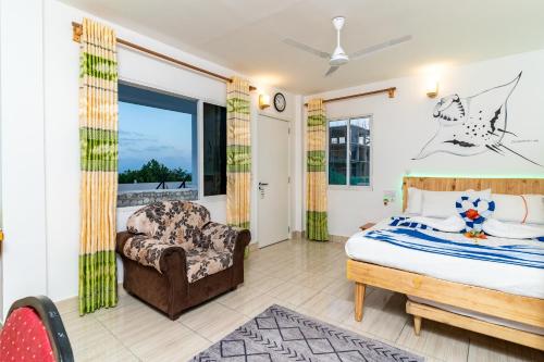 a bedroom with a bed and a chair at Olhumathi View Inn in Ukulhas