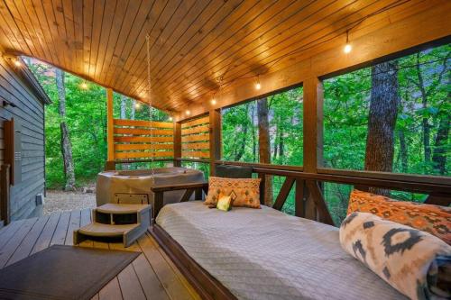 un porche d'une cabine avec un lit et un bureau dans l'établissement Silver Linings, à Broken Bow