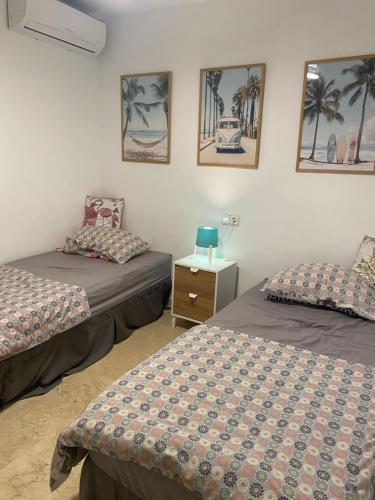 two beds in a room with palm trees and pictures on the wall at Casa Lovia in Orihuela Costa