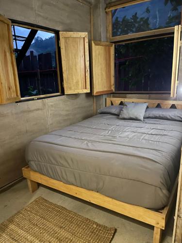 una cama en una habitación con dos ventanas en EB5 Escape Tzununa, Lake Atitlan Room #3 - two minute walk to the Lake, en Tzununá