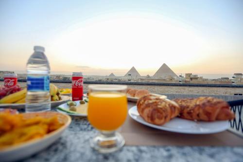 开罗The SACRED ANGLE pyramids view的一张桌子,上面放着一盘食物和一杯橙汁