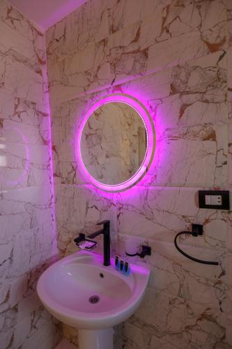 a bathroom with a white sink and a pink lighted mirror at The Sacred Angle pyramids View in Cairo
