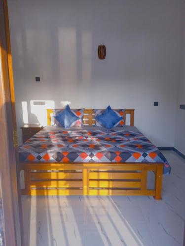 a bedroom with a wooden bed with blue pillows at Free Breeze Guest & Villa in Weligama